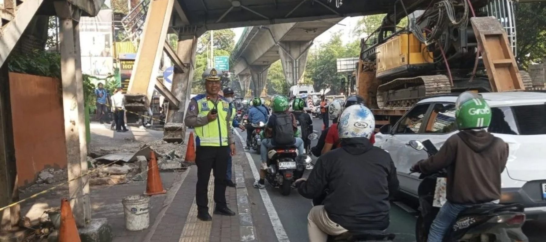 Petugas Ditlantas Polda Metro Jaya sedang melakukan pengaturan di lokasi tempat kejadian truk yang membawa muatan alat berat hingga tersangkut di Jembatan Penyeberangan Orang (JPO) di kawasan Mampang Prapatan, Jakarta Selatan, Selasa, 14 Juli 2026.