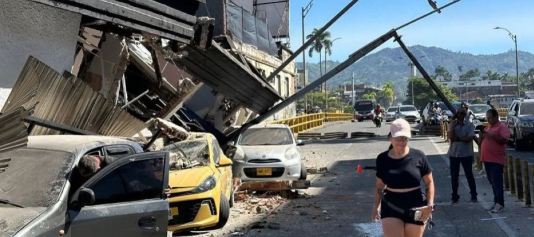 Seorang warga berjalan di dekat sejumlah kendaraan roda empat yang ringsek tertimpa bangunan roboh setelah gempa bumi berkekuatan magnitudo 6,8 mengguncang Kolombia, menewaskan setidaknya 18 orang dan menyebabkan kerusakan di Pereira, Kolombia, Senin