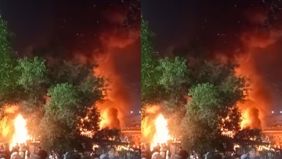 Api merambat ke bangunan rumah lainnya. Petugas pemadam kebakaran berusaha memadamkan api.