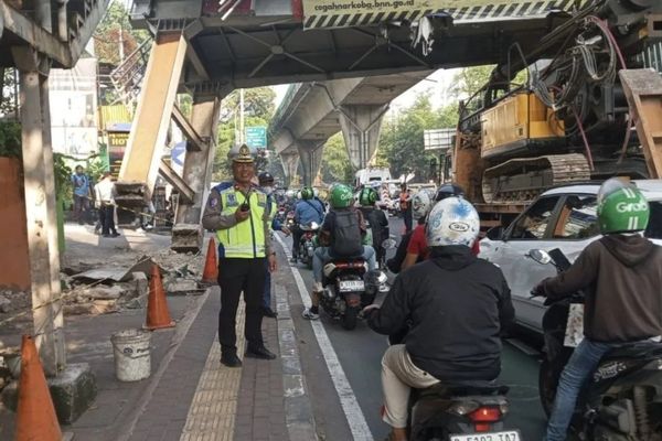 Petugas Ditlantas Polda Metro Jaya sedang melakukan pengaturan di lokasi tempat kejadian truk yang membawa muatan alat berat hingga tersangkut di Jembatan Penyeberangan Orang (JPO) di kawasan Mampang Prapatan, Jakarta Selatan, Selasa, 14 Juli 2026.