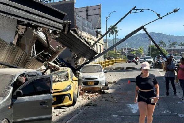 Seorang warga berjalan di dekat sejumlah kendaraan roda empat yang ringsek tertimpa bangunan roboh setelah gempa bumi berkekuatan magnitudo 6,8 mengguncang Kolombia, menewaskan setidaknya 18 orang dan menyebabkan kerusakan di Pereira, Kolombia, Senin