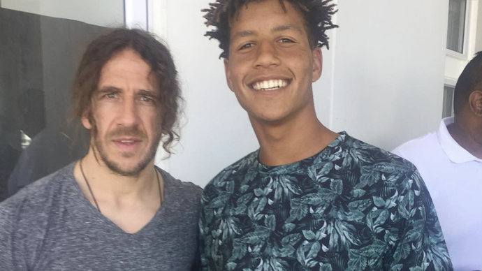 Mendiang Luke Fleurs, bek masa depan Afrika Selatan berfoto dengan mantan bek Barcelona, Carles Puyol. (Instagram @LukeFleurs25).