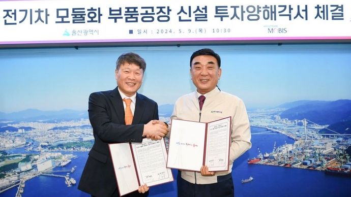 CEO Hyundai Mobis Lee Gyu-suk (kiri) dan Wali Kota Ulsan Kim Du-gyeom berjabat tangan setelah menandatangani perjanjian untuk pabrik modul kendaraan listrik baru di Balai Kota Metropolitan Ulsan pada Kamis (9/5/2024). (Foto: Hyundai Mobis via The Korea Herald) 