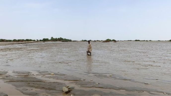 Seseorang berjalan melewati air banjir, di Port Sudan