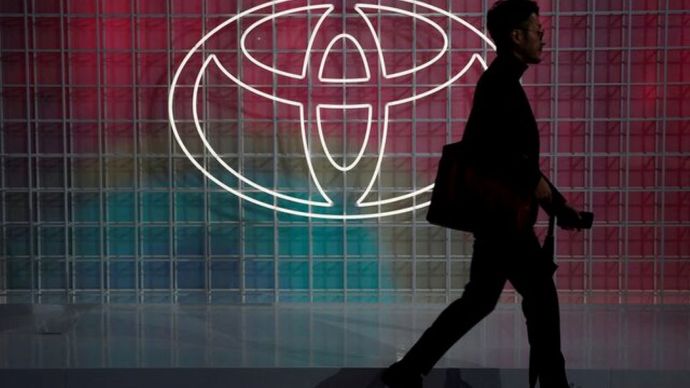 Seorang pria berjalan melewati logo Toyota di Tokyo Motor Show, di Tokyo, Jepang, 24 Oktober 2019. (Foto: Dok/Edgar Su/Reuters)