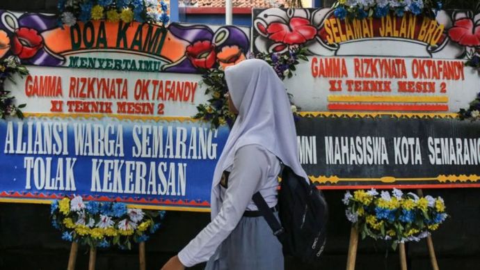 Seorang siswa melintasi karangan bunga untuk kepada siswa korban penembakan oleh oknum polisi usai Aksi Usut Tuntas Penembakan Siswa di depan SMKN 4 Semarang, Semarang, Jawa Tengah, Selasa (26/11/2024).