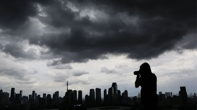 Seorang warga memotret awan tebal yang menyelimuti permukiman dan gedung bertingkat di Jakarta, Kamis (5/12/2024).