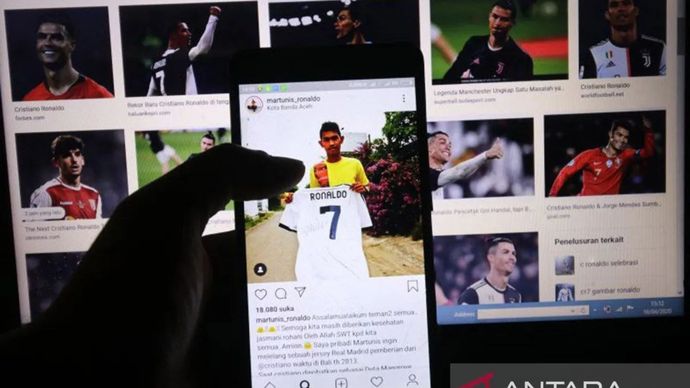 Arsip Foto - Warga mengamati akun instagram anak angkat bintang sepakbola Juventus Cristiano Ronaldo, Martunis di Kota Kediri, Jawa Timur, Kamis (16/4/2020). Penyintas tragedi tsunami Aceh 2004 tersebut melelang jersey pemberian ayah angkatnya melaui instagram untuk membantu menangani pandemi COVID-19