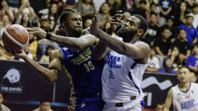 Pebasket Prawira Harum Bandung De Vaughn Lamar (kiri) berusaha mengoper bola yang dihadang pebasket Satria Muda Pertamina Jakarta Wendell Lewis (kanan) saat pertandingan pembuka Indonesia Basketball League (IBL) 2025 di C-Tra Prawira Arena, Bandung, Jawa Barat, Sabtu (11/1/2025).