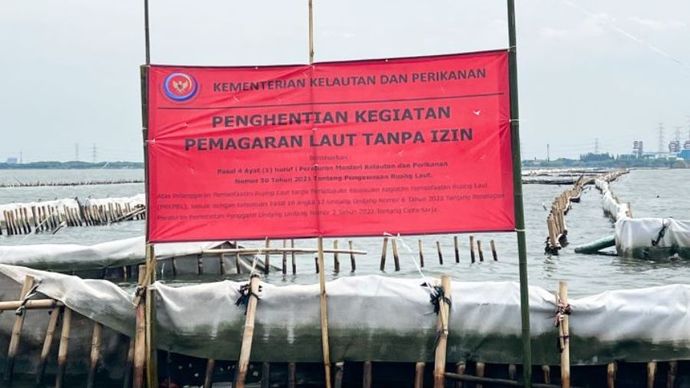 Spanduk berwarna merah dari KKP bertuliskan Kementerian Kelautan dan Perikanan Penghentian Kegiatan Reklamasi Tanpa PKKPRL terpasang di pagar laut perairan Bekasi, Rabu (15/1/2025). <b>(Dok.Antara)</b>