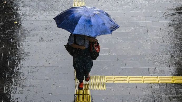 Warga menggunakan payung untuk menorobos hujan lebat di pedestrian Jalan Jenderal Sudirman, Jakarta, Sabtu (25/1/2025). 