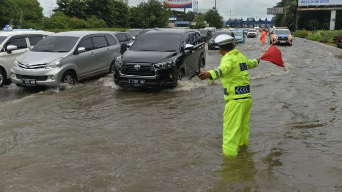 Petugas mengatur lalulintas kendaraan di ruas Tol Sedyatmo, Cengkareng, Jakarta Barat yang terendam banjir.