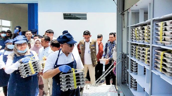 Menko Bidang Pangan Zulkifli Hasan bersama Bupati Banyuwangi Ipuk Fiestiandani menaikkan makanan ke atas pikap untuk didistribusikan ke sekolah dari SPPG Kecamatan Rogojampi, Kabupaten Banyuwangi, Jawa Timur, Senin (3/2/2025)