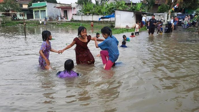 Ilustrasi - Sejumlah bocah bermain di atas genangan air banjir yang merendam kawasan permukiman di Kabupaten Tangerang