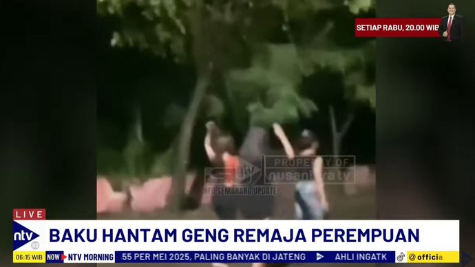 Tampak dua geng remaja perempuan terlibat dalam perkelahian di tengah jalan pada malam hari. 