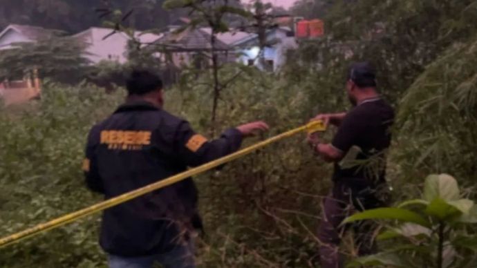 Anggota Kepolisian saat memasang garis polisi di lokasi penemuan jasad perempuan di ampung Kedokan RT.009/002, Desa Cibogo Kecamatan Cisauk, Kabupaten Tangerang pada Rabu (16/7/2025).