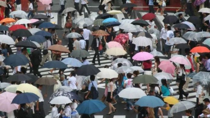 Orang-orang berjalan di tengah hujan di Shibuya, pusat kota Tokyo, Jepang