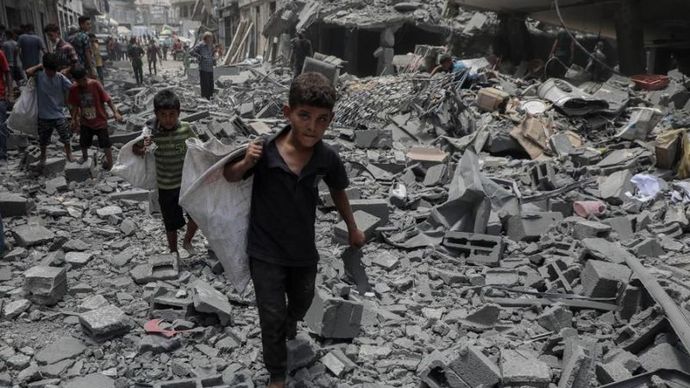 Anak-anak berjalan di atas reruntuhan bangunan setelah serangan udara Israel di wilayah Al-Rimal, sebelah barat Kota Gaza, pada 8 Agustus 2025. (Xinhua/Rizek Abdeljawad)