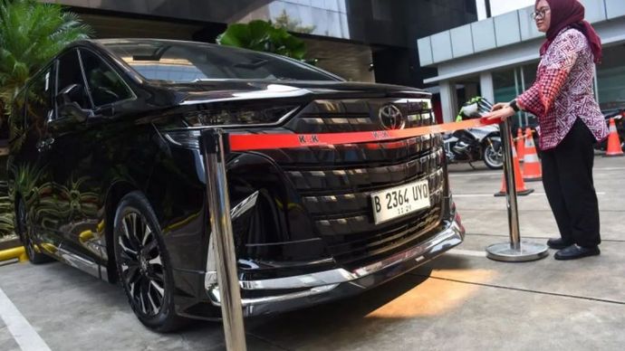 Karyawan KPK memasang batas pengaman di mobil Alphard yang disita sebagai barang bukti kasus dugaan pemerasan pengurusan sertifikat K3 di Kementerian Ketenagakerjaan, di Gedung Merah Putih KPK, Jakarta, Selasa (26/8/2025).