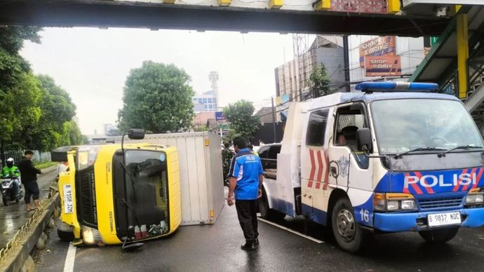 Sebuah truk bermuatan alat konveksi dan benang jahit terbalik di Jalan Raya Matraman, Jakarta Timur, akibat jalan licin usai diguyur hujan, Selasa (9/9/2025).