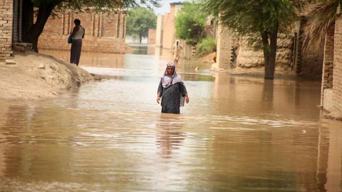 Seorang perempuan berjalan melewati genangan banjir di daerah yang terlanda banjir di pinggiran Multan, Pakistan, pada 2 September 2025. 