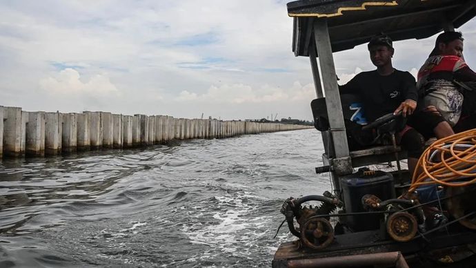 Nelayan melintas di dekat proyek tanggul beton di perairan Cilincing, Jakarta, Kamis, 11 September 2025. Kementerian Kelautan dan Perikanan menyatakan tanggul beton tersebut bukan proyek tanggul laut melainkan proyek pengembangan terminal logistik PT Karya Citra Nusantara yang telah mengantongi izin Persetujuan Kesesuaian Kegiatan Pemanfaatan Ruang Laut. 