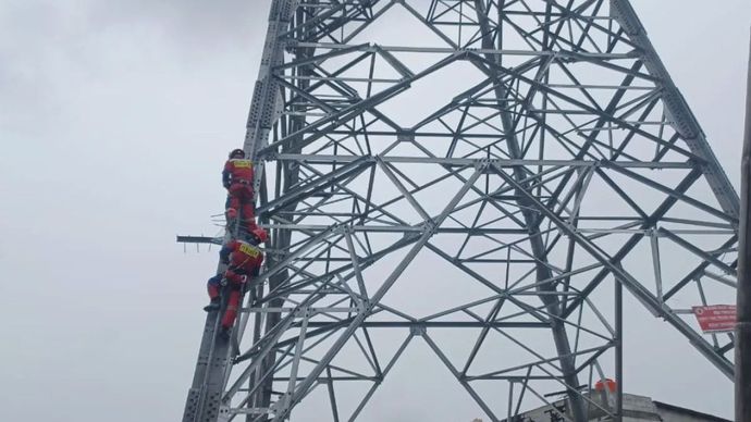Petugas memanjat menara SUTET di kawasan Koja, Jakarta Utara untuk mengevakuasi seorang pria yang memanjat menara tersebut pada Kamis, 18 September 2025.