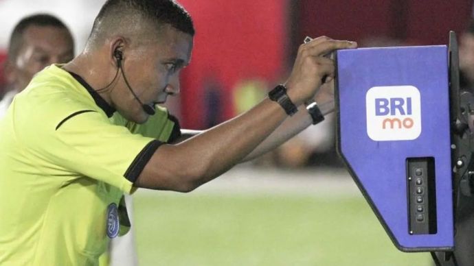 Wasit Agung Setiayawan (kanan) melihat Video Assistant Referee (VAR) setelah pesepak bola Malut United dijatuhkan penjaga gawang Borneo FC Nadeo Winata pada laga lanjutan BRI Liga 1 di Stadion Gelora Kie Raha Ternate, Maluku Utara, Senin (10/2/2025). Tuan rumah Malut United mengalahkan tamunya Borneo FC Samarinda dengan skor 3-0. 