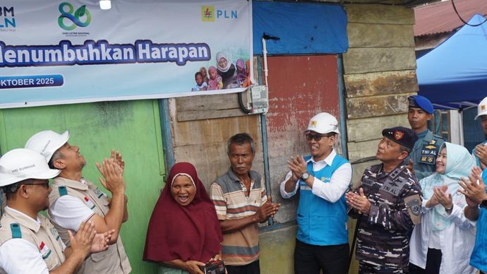 Momen penyalaan sambungan listrik program “Berbagi Cahaya, Menumbuhkan Harapan” oleh Direktur Manajemen Risiko PLN, Adi Lumakso (ketiga dari kanan), di rumah salah satu penerima manfaat, Nazaruddin (tengah). Rasa haru dan bahagia terpancar dari pasangan suami istri ini saat rumah mereka akhirnya memiliki sambungan listrik mandiri.