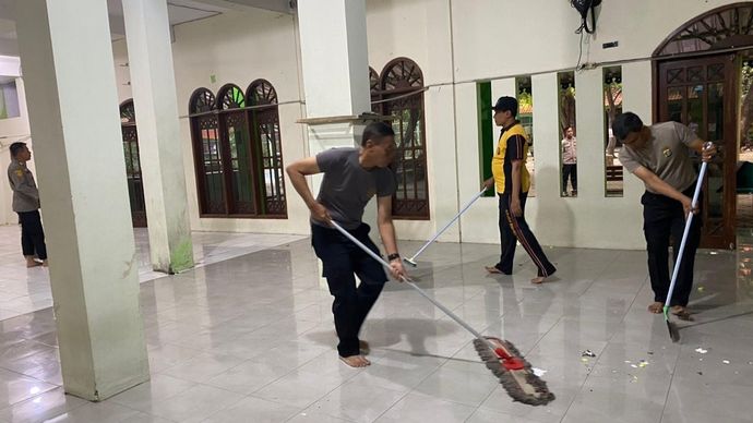 Petugas kepolisian membersihkan masjid di kompleks SMAN 72 Jakarta. 
