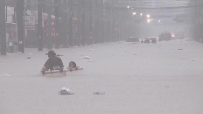 Orang-orang berpegangan pada puing-puing yang mengapung selama banjir dahsyat&nbsp;di&nbsp;Thailand.