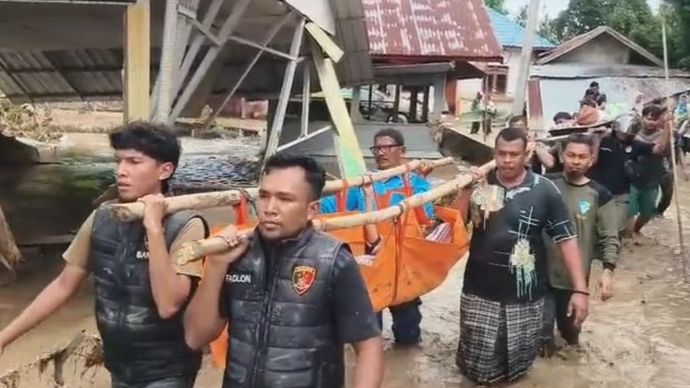 Polisi dan warga menggotong jenazah santri yang hanyut di Aceh. 