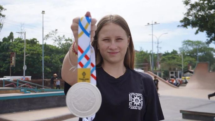 Atlet skateboard Indonesia asal Bali Ni Wayan Malana Fairbrother saat ditemui di Kuta Beach Skatepark, Badung, Minggu (21/12), menunjukkan medali perak yang diraihnya pada nomor street putri SEA Games 2025 di Thailand. (Antara/ Rita Laura)