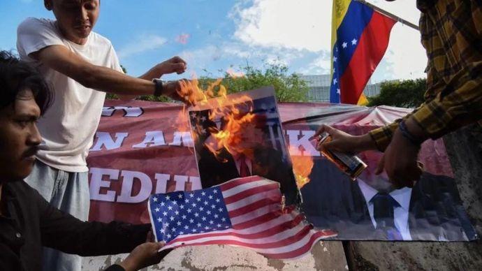 Pengunjuk rasa dari berbagai aliansi membakar bendera AS dan poster bergambar presiden AS Donald Trump saat menggelar aksi solidaritas untuk Venezuela di depan Kedutaan Besar Amerika Serikat, Jakarta, Selasa (6/1/2026). Dalam aksi solidaritas tersebut mereka mengecam tindakan penyerangan dan penangkapan terhadap Presiden Venezuela Nicolas Maduro berserta istrinya oleh Amerika Serikat dan meminta agar Indonesia untuk menyatakan sikap resmi, serta mendukung rakyat Venezuela menentukan nasib negaranya tanpa intervensi asing. ANTARA FOTO/Indrianto Eko Suwarso/YU
