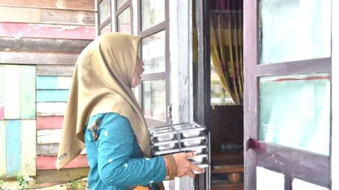 Seorang tim pendamping keluarga (TPK) sedang mengantarkan Makan Bergizi Gratis (MBG) untuk sasaran ibu hamil, ibu menyusui, dan balita ke rumah penerima manfaat. ANTARA/HO-Kemendukbangga/BKKBN.