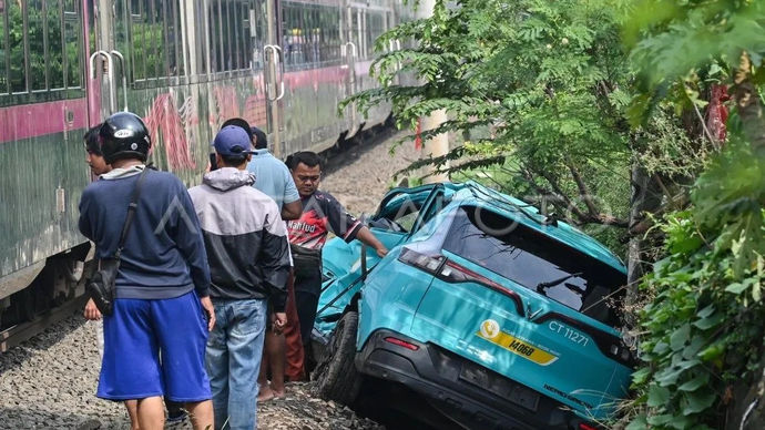 Kereta api (KA) jarak jauh melintas di samping taksi listrik Green SM yang rusak pascakecelakaan KRL Commuter Line dan KA Argo Bromo Anggrek di Stasiun Bekasi Timur, Bekasi, Jawa Barat, Selasa (28/4/2026). Komite Nasional Keselamatan Transportasi (KN