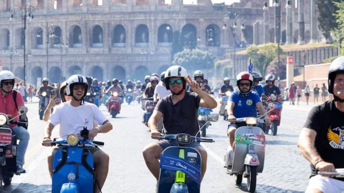 Para pengendara Vespa berkendara melewati Colosseum pada hari terakhir "Vespa Roma 2026 - 80 Tahun Sebuah Ikon", sebuah pertemuan global selama empat hari yang menandai ulang tahun ke-80 merek skuter ikonik Italia, di Roma, Italia, 27 Juni 2026. (Foto: Dok/Remo Casilli/Reuters) 