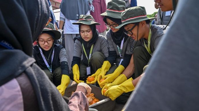 Para peserta program Greenbus Pertamina 2026 Season 2 sedang melalukan pemilahan sisa makanan untuk diolah menjadi pakan magot di Kampung Hijau Cemara, Jakarta, Kamis, (2/7/2026).