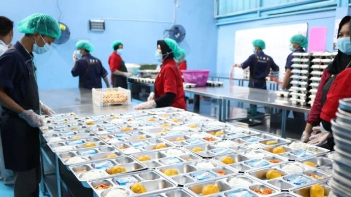 Ilustrasi - Petugas satuan pelayanan pemenuhan gizi (SPPG) menyajikan menu makanan yang akan didistribusikan ke sekolah dalam program MBG.