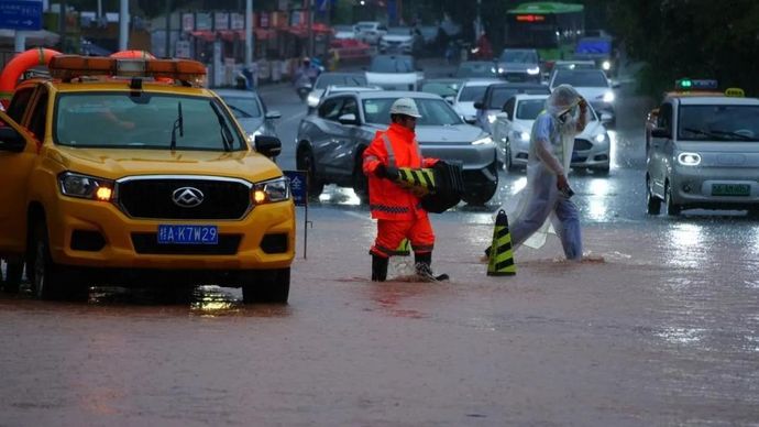 Seorang petugas memasang rambu peringatan di ruas jalan yang tergenang air di Nanning, Daerah Otonomi Guangxi Zhuang, China, pada Minggu,  5 Juli 2026. 