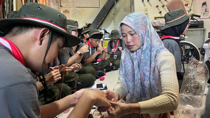 Penyandang disabilitas tuna daksa sekaligus perajut kain, Elis Juarsih (47) mengajarkan cara membuat gelang dengan merajut benang kepada anggota Green Warriors diacara Green Bus Pertamina 2026, rabu (8/7) di Kampoeng Radjoet Binong.