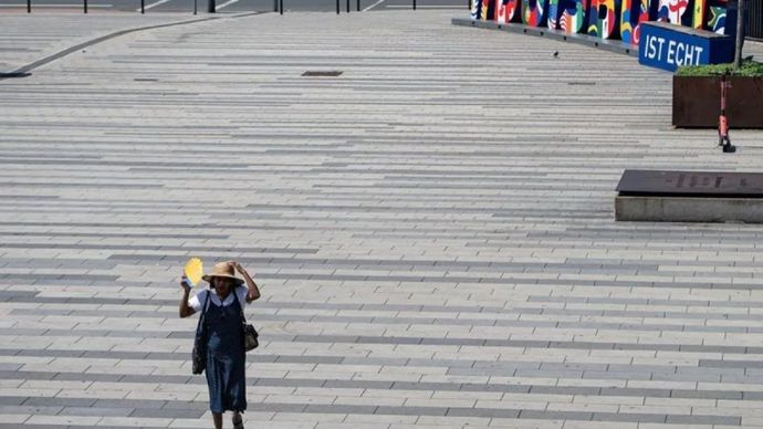 Seorang wanita berjalan di bawah sinar matahari saat gelombang panas dengan suhu mendekati 40 derajat Celsius di Duisburg, Jerman, Rabu, 24 Juni 2026.