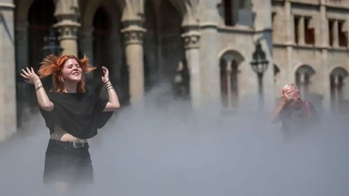 Seorang wanita sedang mendinginkan badan di sebuah sistem kabut pendingin saat gelombang panas di Budapest, Hongaria, Rabu, 24 Juni 2026.