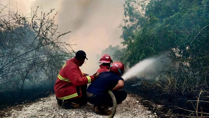Petugas saat memadamkan api di Tanjung Saguk, Kabupaten Natuna, Provinsi Kepulauan Riau pada Ahad