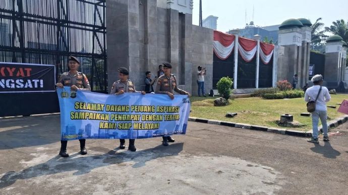 Personel kepolisian membentangkan spanduk bertuliskan &ldquo;Selamat Datang Pejuang Aspirasi, Sampaikan Pendapat dengan Tertib, Kami Siap Melayani&rdquo; di depan kawasan parlemen Jakarta pada Senin, 24 Agustus 2026.