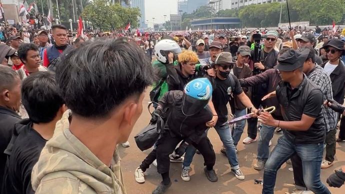 Pemuda berkacamata meringkus pria berhelm biru yang membawa golok saat demo di depan Gedung DPR RI. 