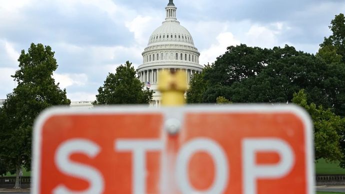 Foto yang memperlihatkan rambu tanda berhenti dengan gedung Capitol AS sebagai latar belakang di Washington, D.C., Amerika Serikat.