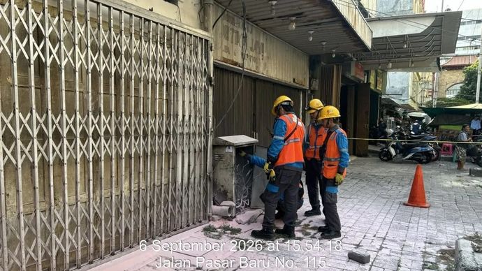 Petugas menangani kepulan asap yang menyembur dari dalam tanah di kawasan pertokoan Pasar Baru, Jakarta Pusat