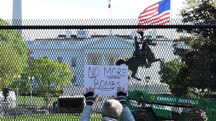 Seorang pengunjuk rasa memegang poster di depan Gedung Putih di Washington, D.C., Amerika Serikat, pada 7 April 2026.