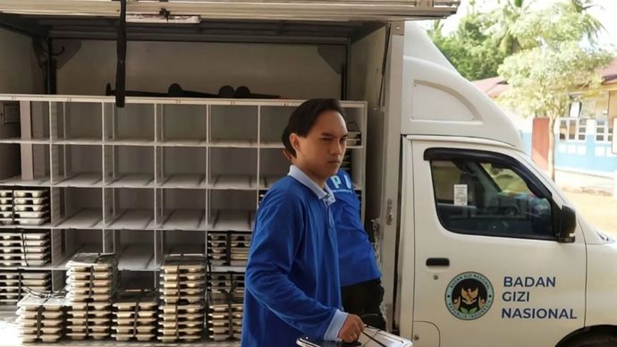 Seorang siswa dan petugas sedang menurunkan ompreng MBG untuk dibagikan ke kelas-kelas.